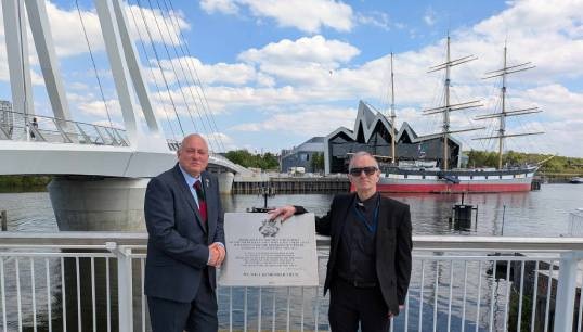 Image:Iain Lindsay (left) at the new plaque with Reverend Joseph O'Donnell, who conducted the blessing. Image: Nautilus International