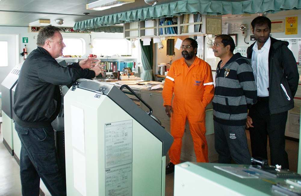 Title: deepsea pilot captain Paul Lanaghan discusses the passage with Cygnus Leaders master and navigational officers
