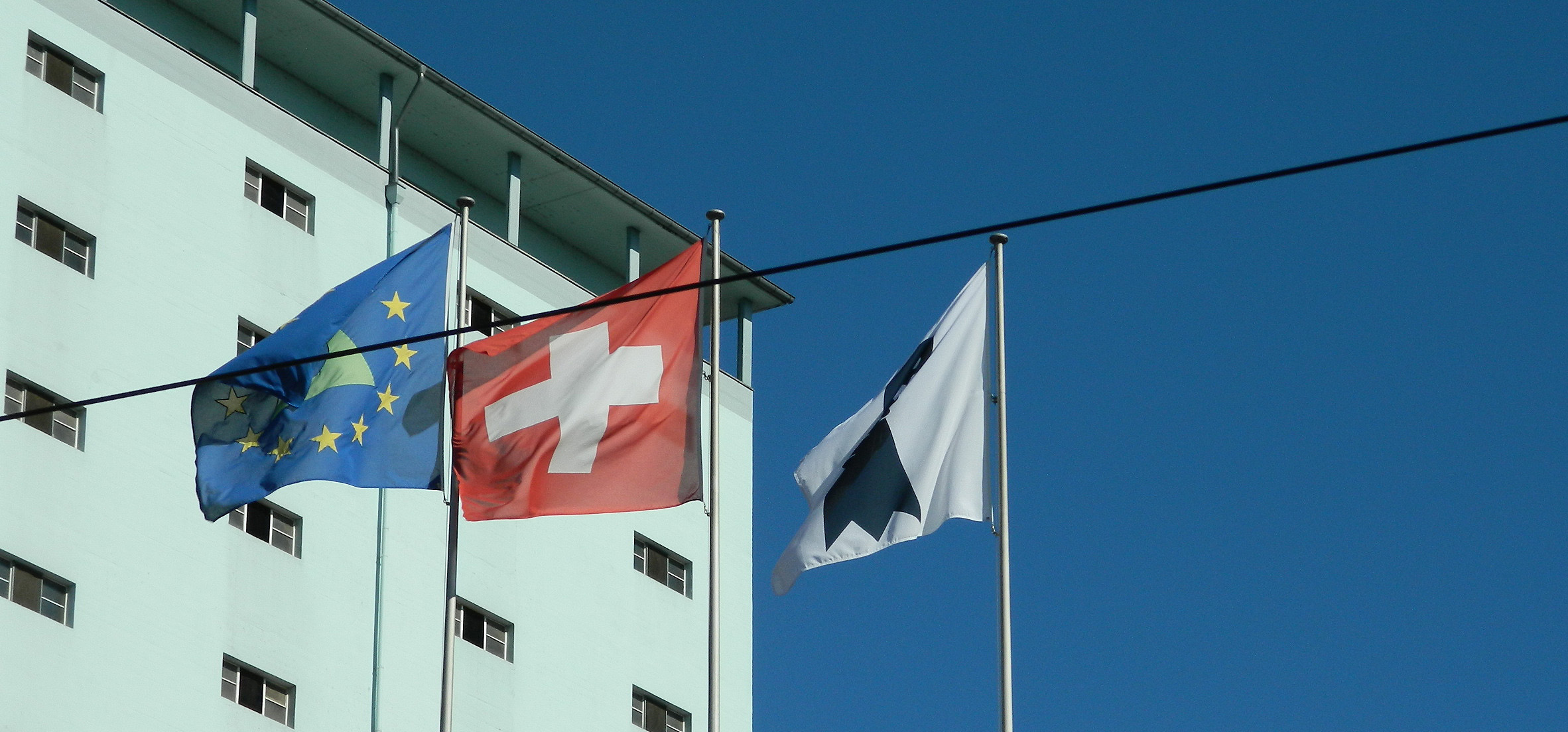 Image:Die drei Flaggen symbolisieren grenzüberschreitende Zusammenarbeit in der Region Basel. Der Rheinknie umringt von europäische Sternen, das Schweizer Kreuz und der Baslerstab.