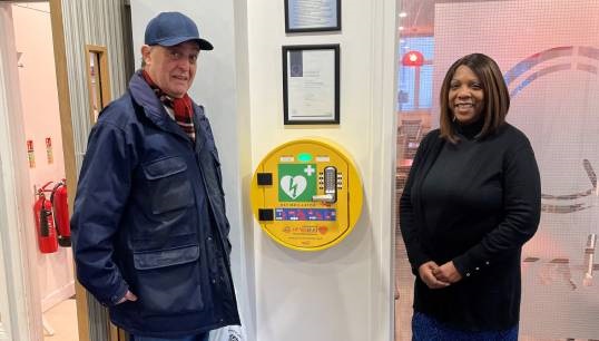 Image:L-R: QVSR Resident Leonard Hann and staff member Claudette Cummings inspect one of the AED's that has already been installed at the QVSR in London by the SHS. Image: QVSR