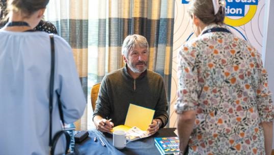 Image:Former Nautilus Telegraph editor Andrew Linington, author of Pulling Together, signs books for members at the launch during the General Meeting in 2023. Image: Brad Wakefield