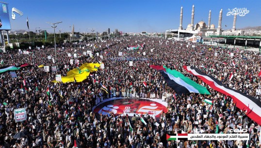 Image:Crowds in Sana'a, the Houthi-controlled capital of Yemen, hold aloft Yemeni and Palestinian flags at a protest against Western missile strikes. The bombings were carried out in retaliation for attacks on shipping by Houthi forces. Image: Wikimedia Commons