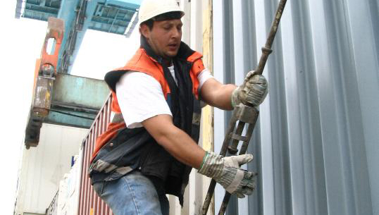 Image:A dock worker lashing a container. Image: Danny Cornelisson