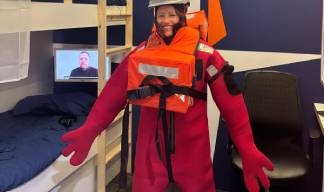 Image:Penny Hogan of Unity Bank dons an immersion suit during a safety drill challenge in the Nautilus ship's cabin stand.