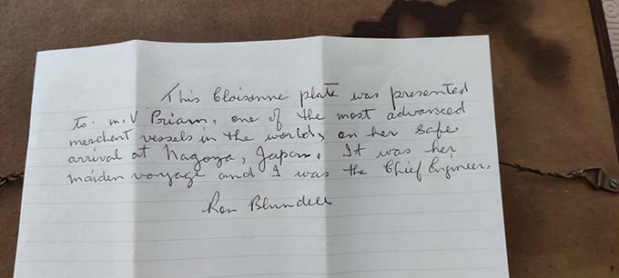 Image:A note from the late Ron Blundell detailing the gift of a wall plaque of Nagoya Castle. The note reads: 'This cloisonne plate was presented to the MV Priam, one of the most advanced merchant vessels in the world, on her safe arrival at Nagoya, Japan. It was her maiden voyage and I was her chief engineer.' Image: Keith Blundell